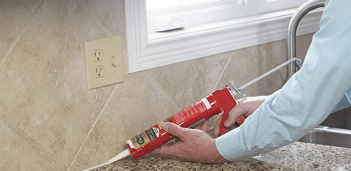 Handyman applying caulk along a kitchen backsplash and countertop seam in Norfolk, VA