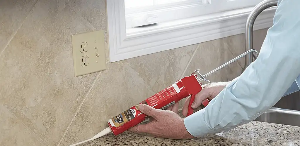 Handyman applying caulk along a kitchen backsplash and countertop seam in Norfolk, VA