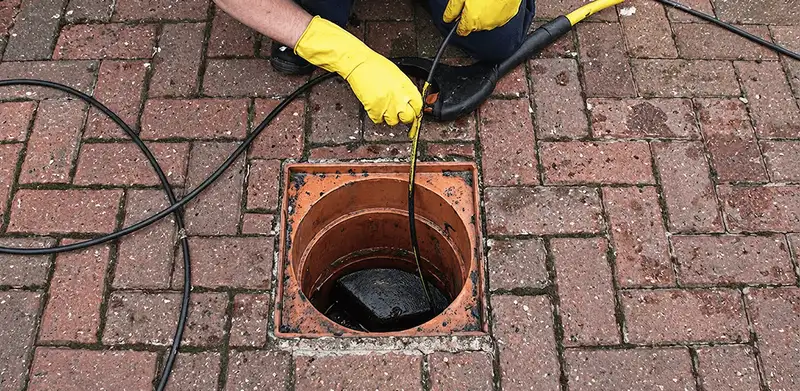 Drain cleaning technician using a drain snake to clear a clogged drain in Norfolk, VA