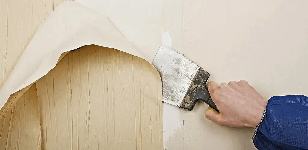 Handyman removing wallpaper with a scraper for wall preparation in Norfolk, VA